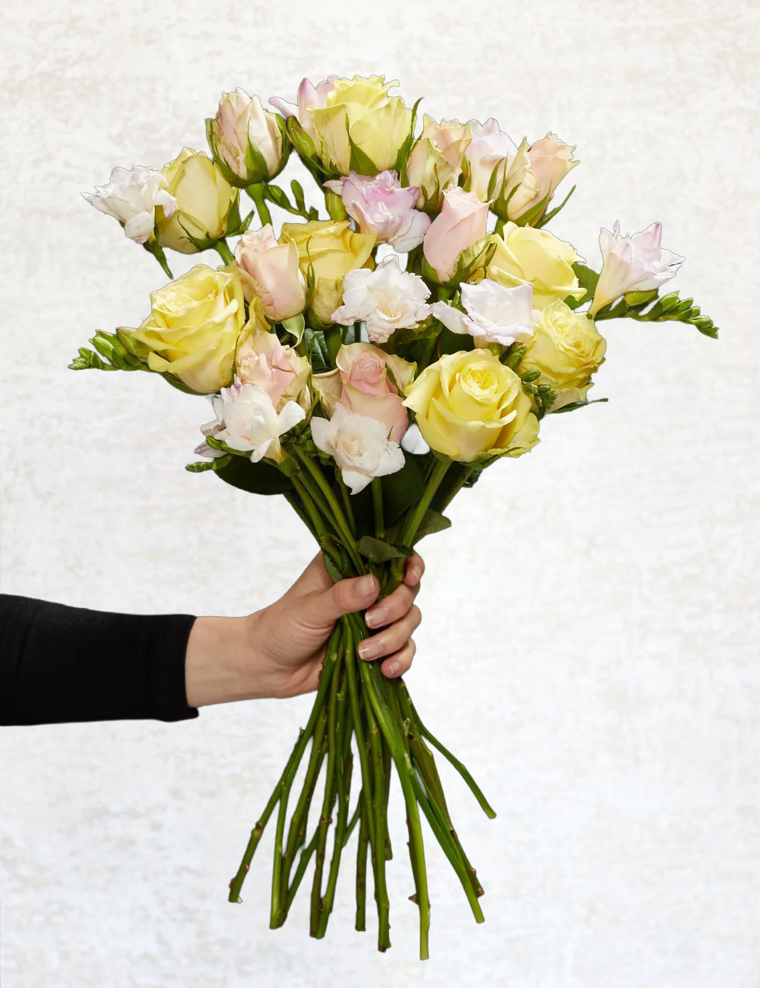 Handheld bouquet of pale yellow and blush roses
