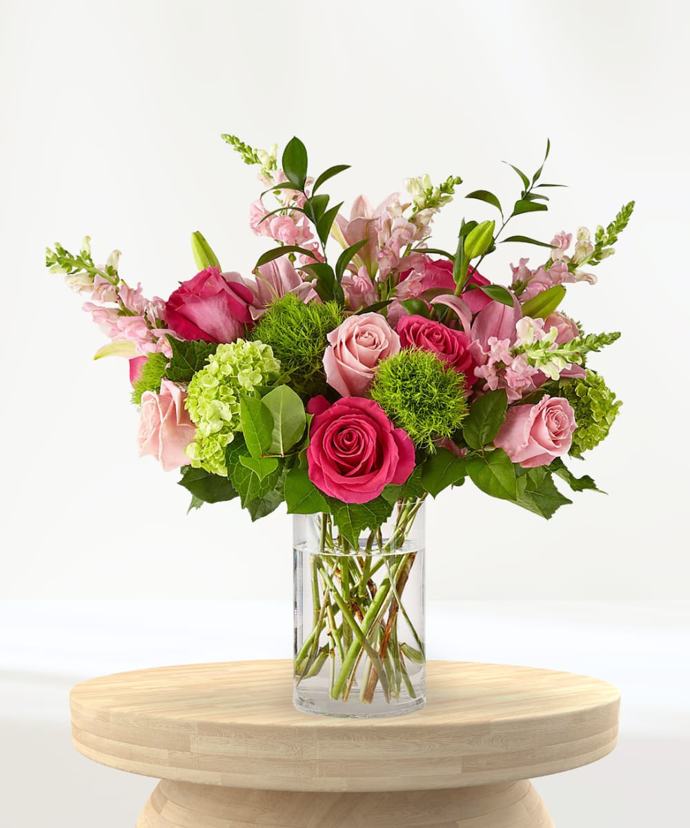 Pink roses and lilies arranged in a clear glass vase