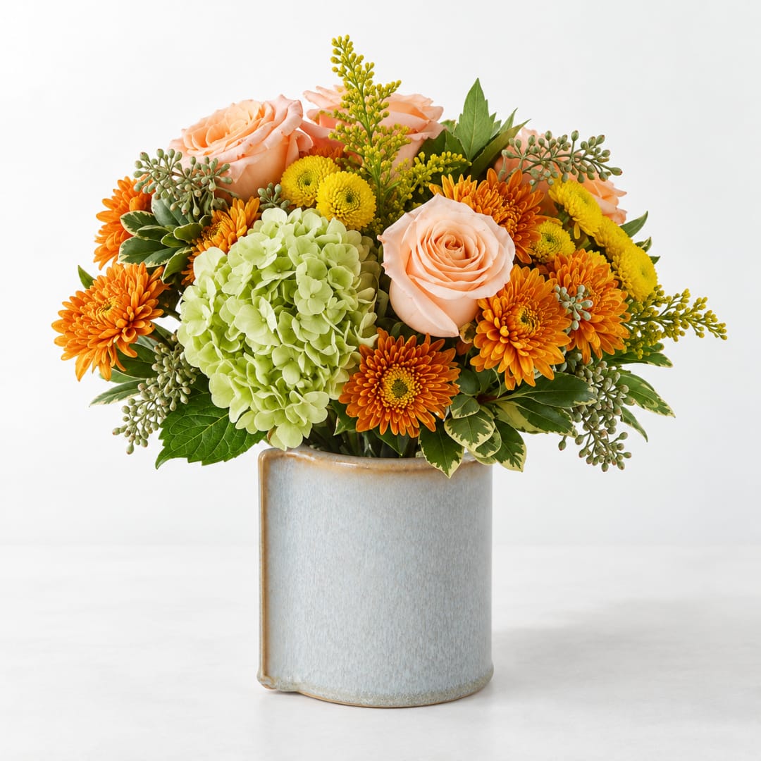 Peach roses and orange mums in a ceramic vase