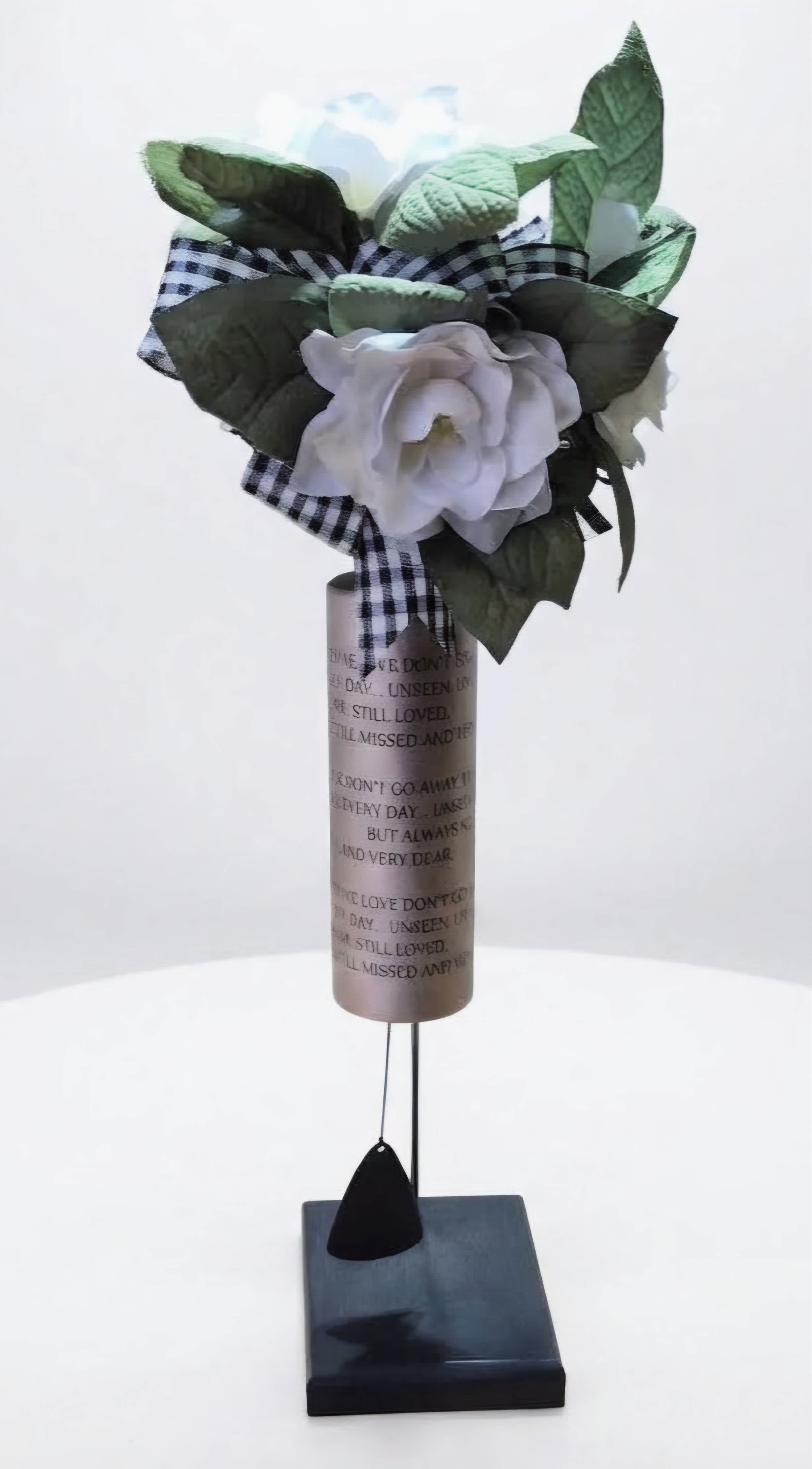 White rose memorial arrangement with a plaid ribbon on a stand