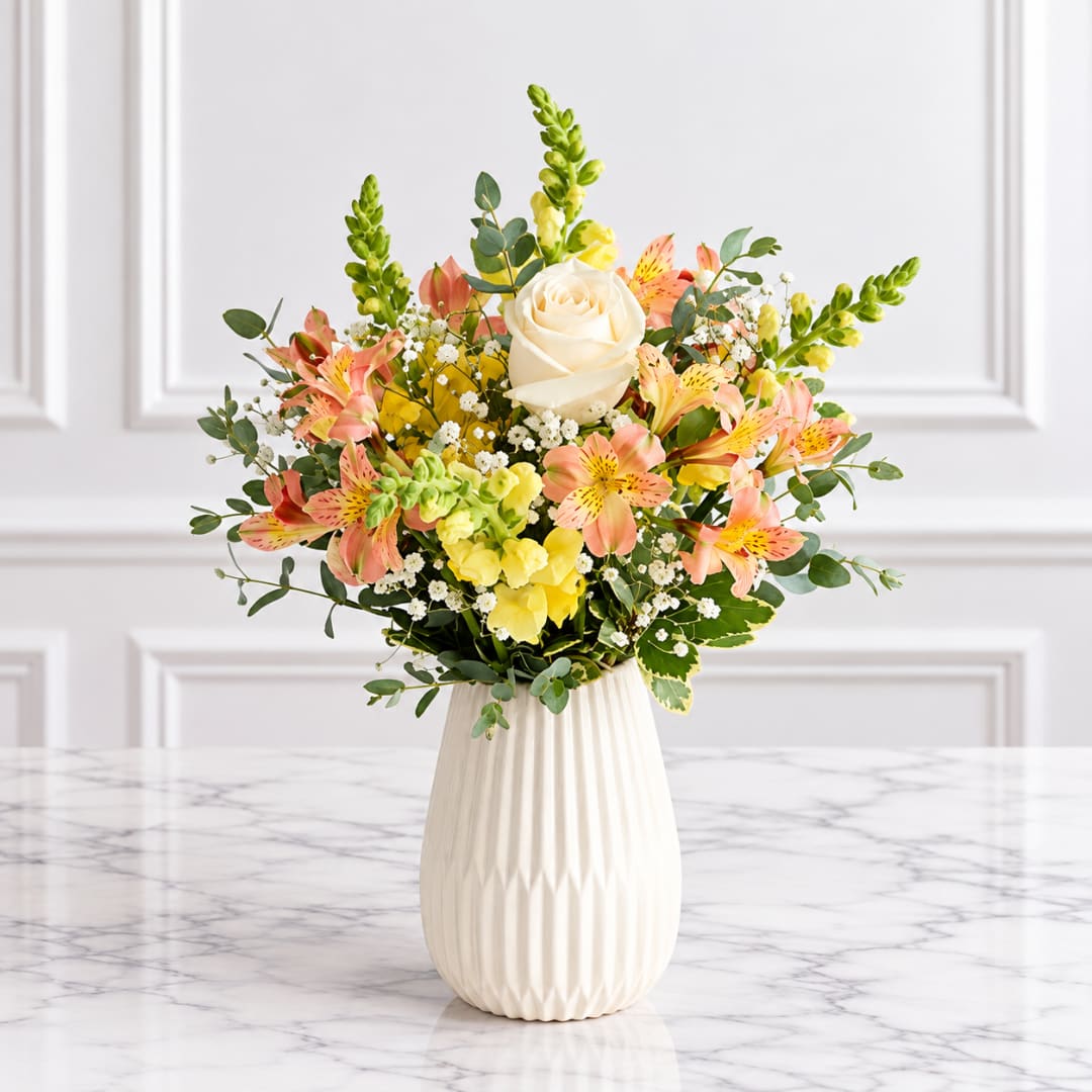 Bouquet of peach and yellow flowers in a white vase