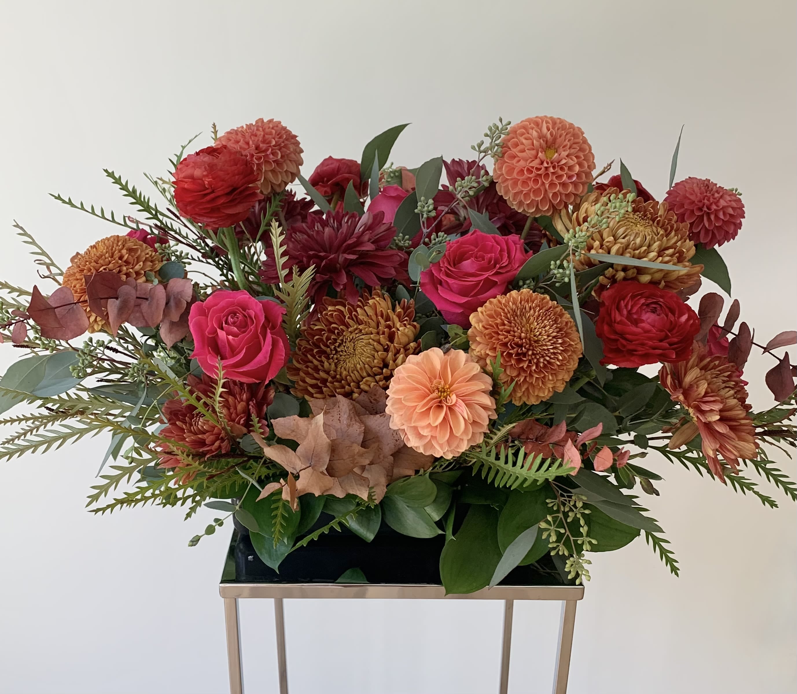Autumn Spirit  - A beautiful seasonal table arrangement designed in a 10x5inch tray, with premium flowers such as roses, cremons, dahlias, germinis, disbuds and seasonal foliage to make a perfect floral treat for yourself or your loved ones. Invite the season into your home or office with Autumn Spirit.