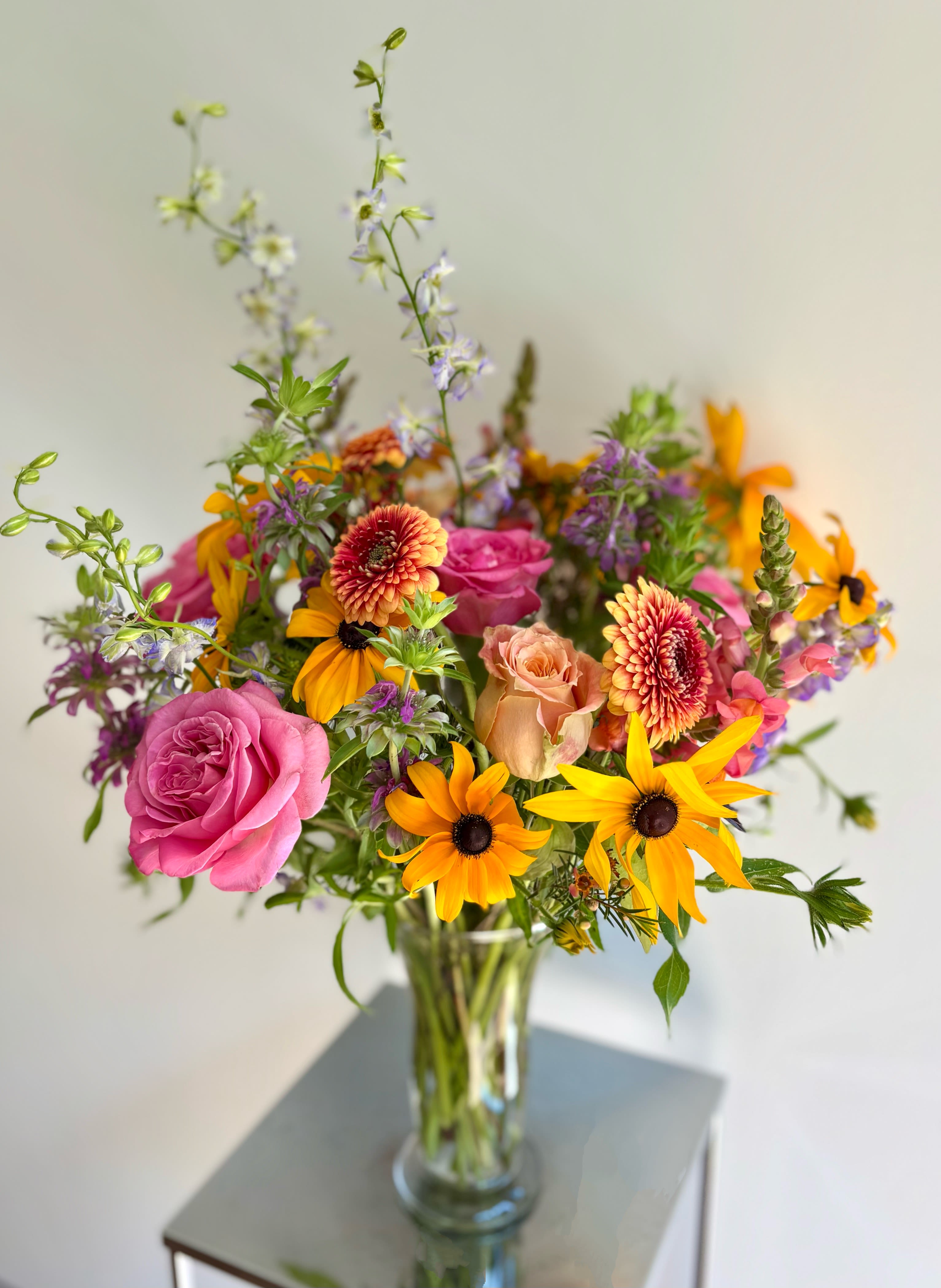 Mixed bouquet of pink roses and orange daisies in a glass vase