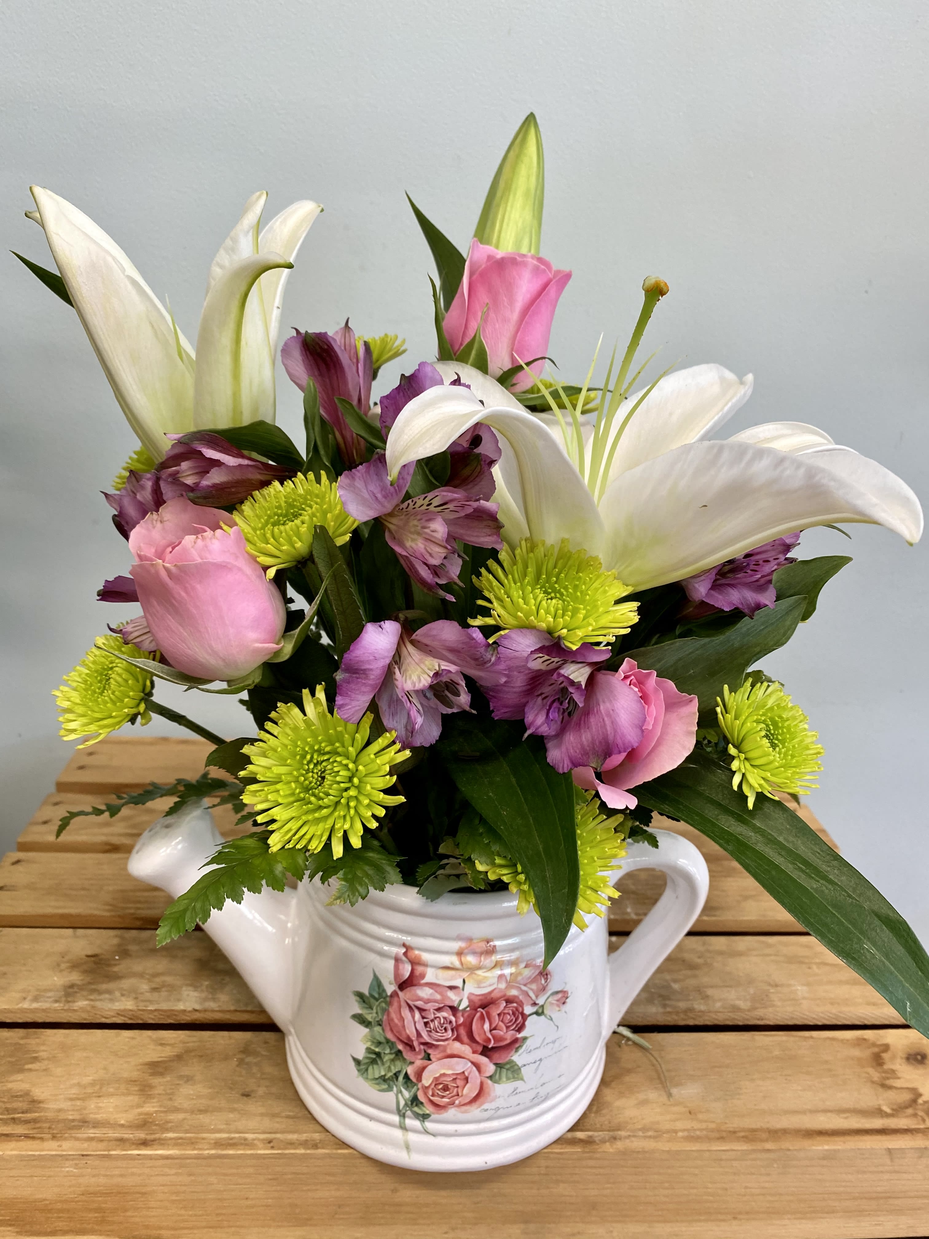Pink and white flowers arranged in a white teapot vase