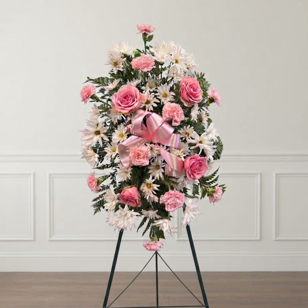 Pink and white floral standing spray on an easel with a ribbon
