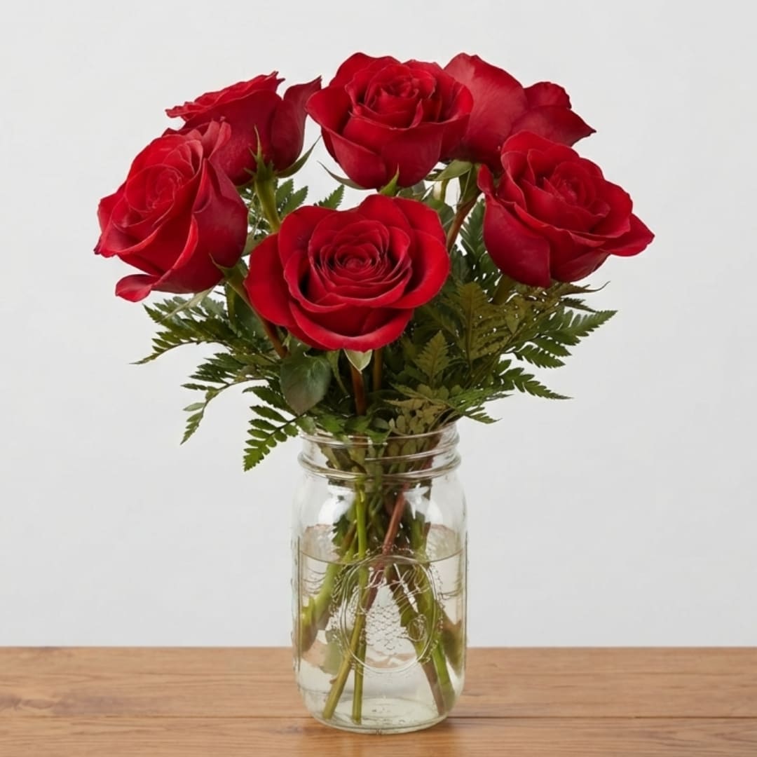 Red roses arranged in a clear glass jar vase
