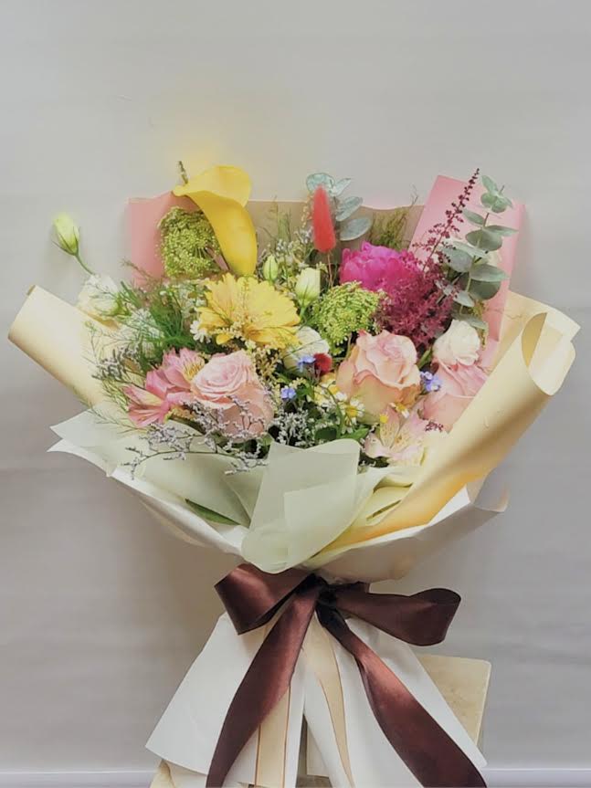 Mixed bouquet with pink roses, yellow calla lilies, and bright filler flowers
