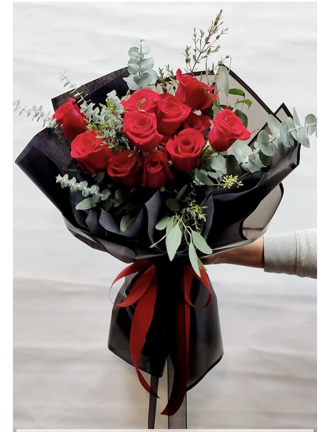 Bouquet of red roses wrapped in black paper with a red ribbon