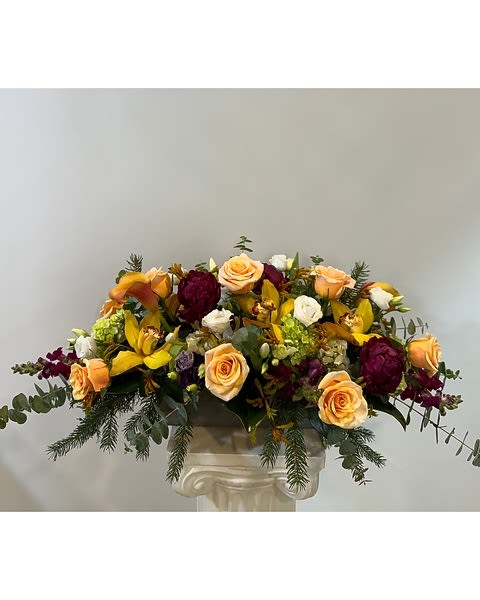 Mixed bouquet of peach roses, yellow blooms, and burgundy flowers in a vase
