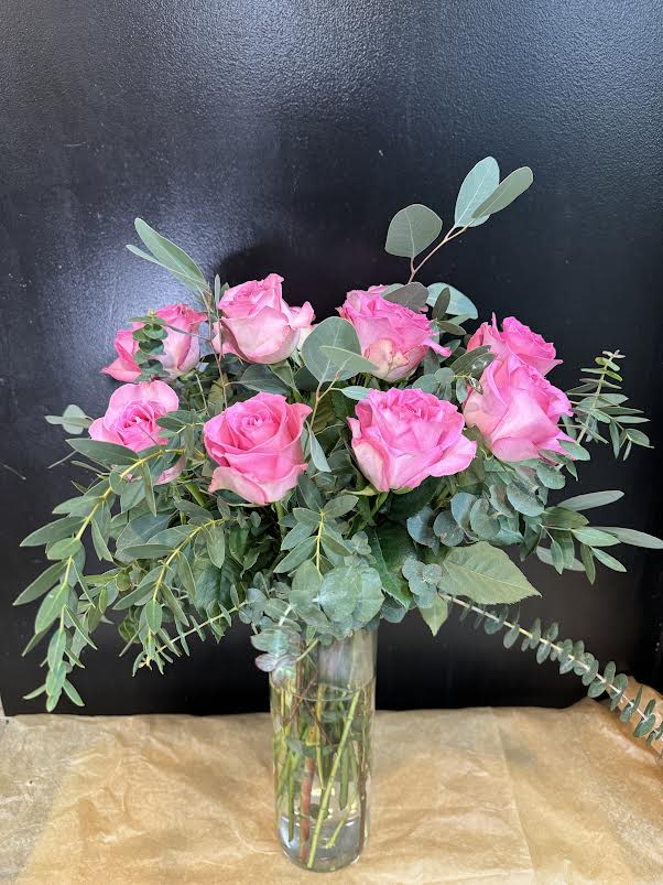 Pink roses in a clear glass vase with eucalyptus