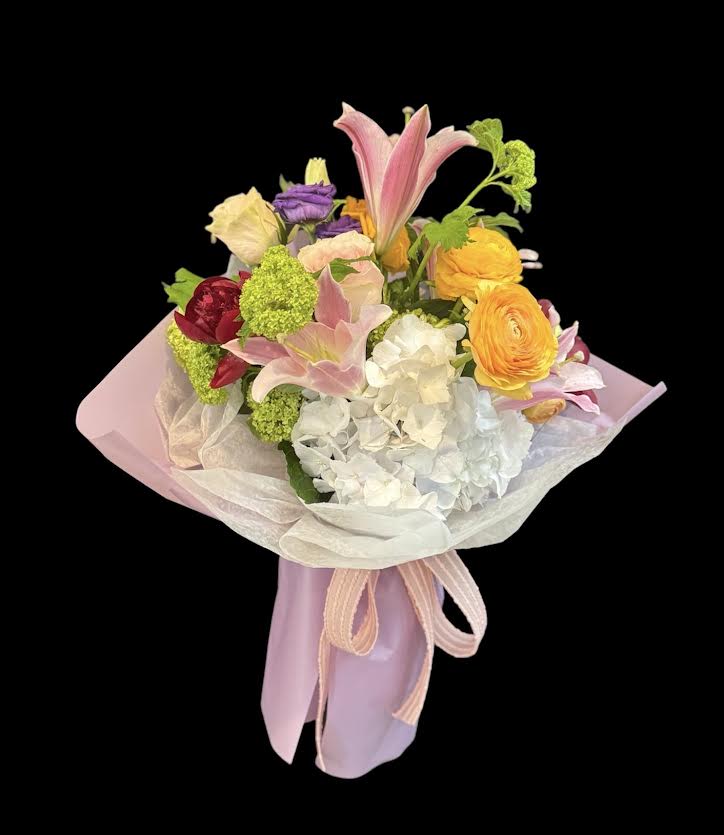 Pastel bouquet with lilies, hydrangea, and ranunculus wrapped in pink paper