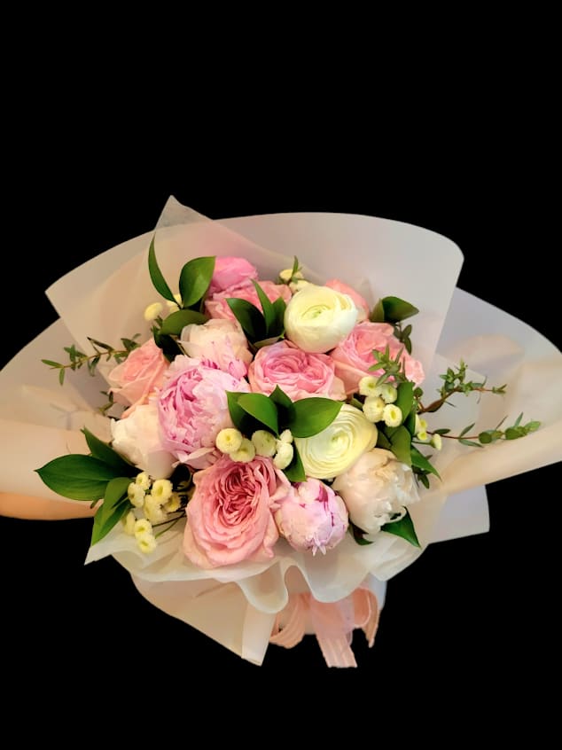 Pink and white bouquet of roses and peonies wrapped in white paper
