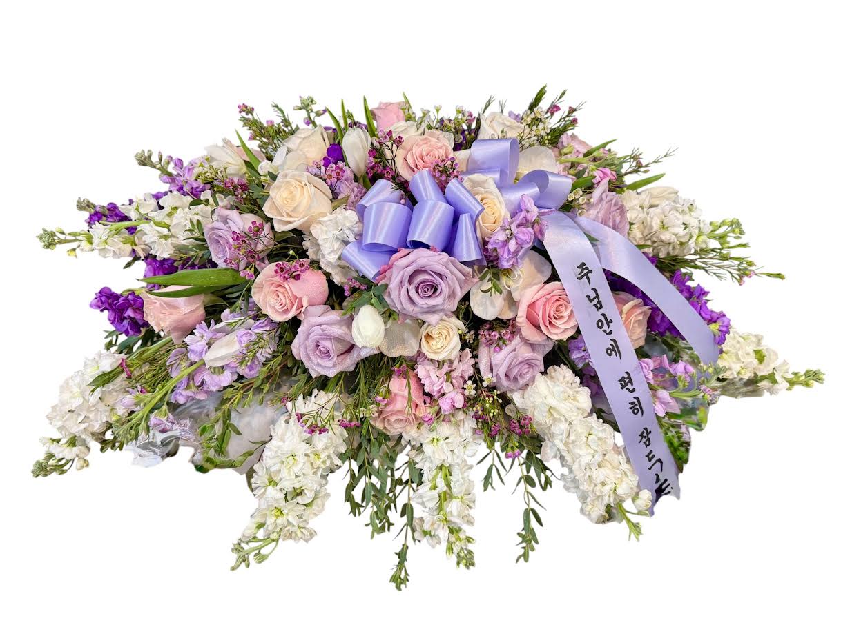 Large pastel floral spray with roses and white blooms, tied with a lavender ribbon