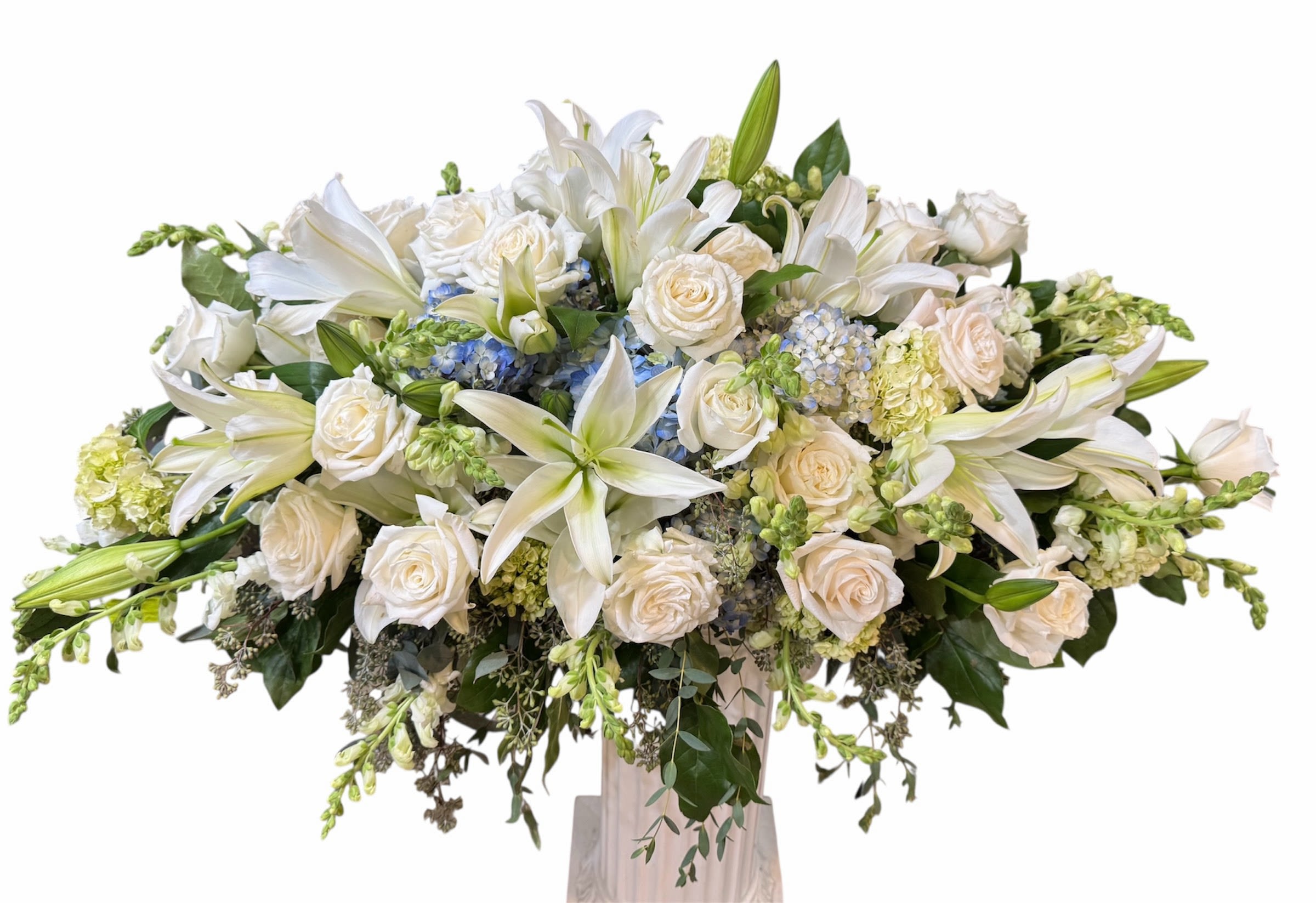 Large white floral arrangement with lilies and roses in a tall vase