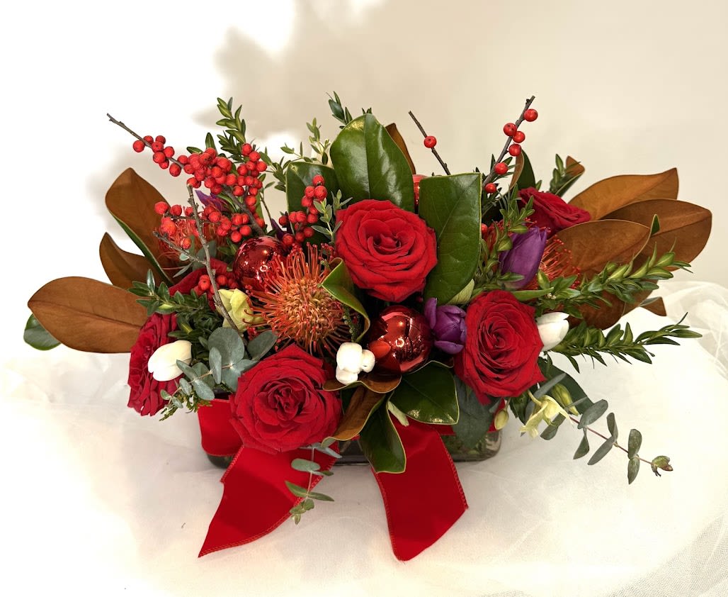Red roses arranged with berries and a red ribbon