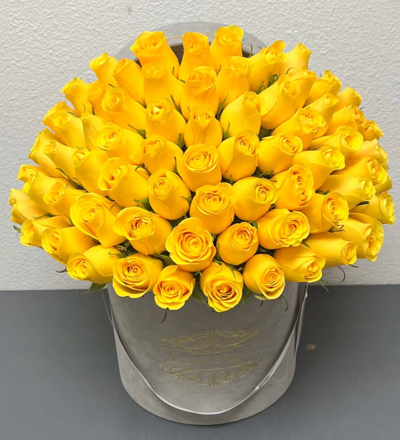 Bouquet of yellow roses in a gray hatbox