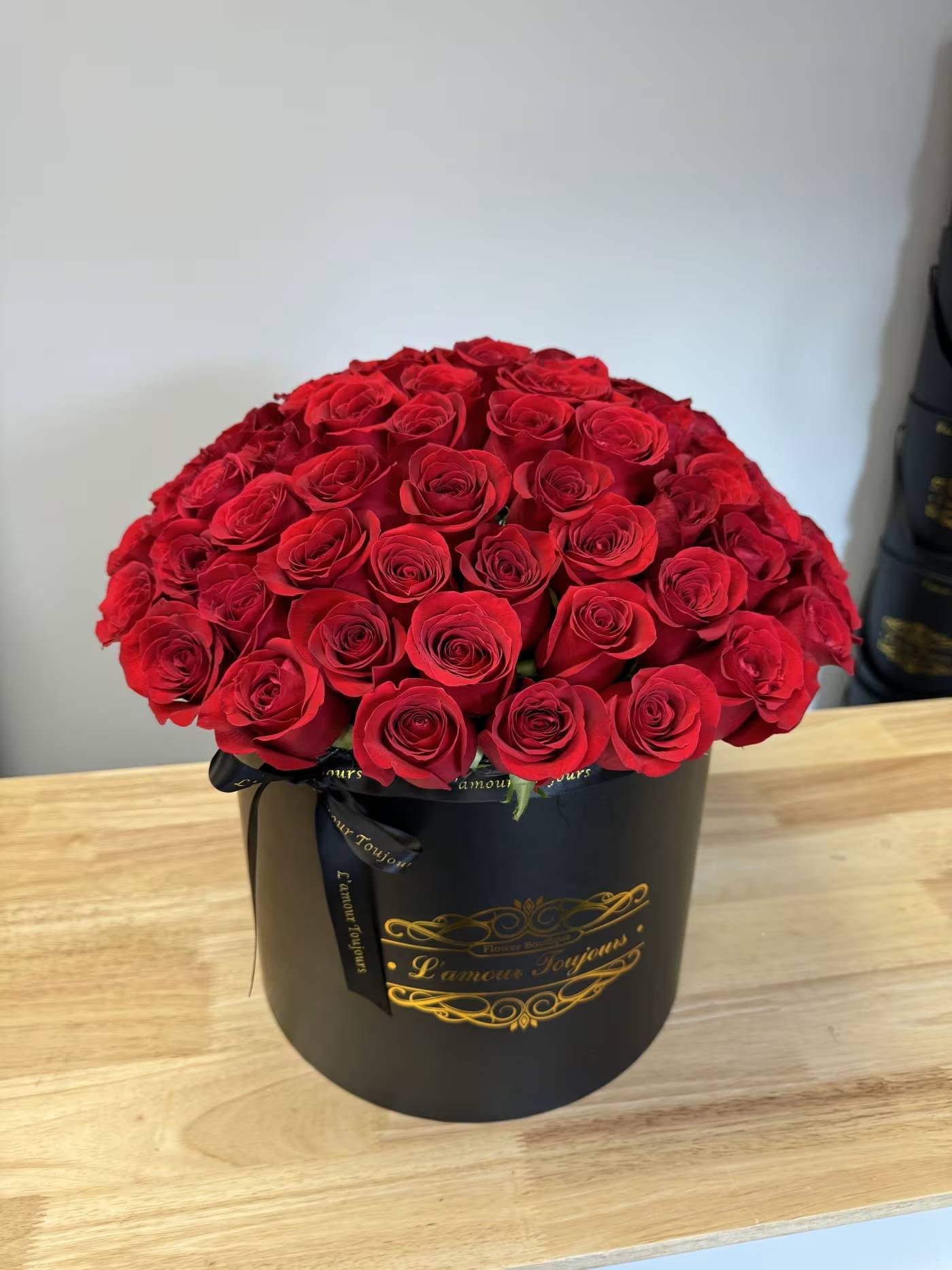 Large bouquet of red roses in a black round box