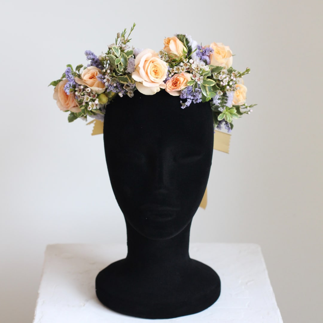 Peach roses and lavender flowers arranged on a black mannequin head