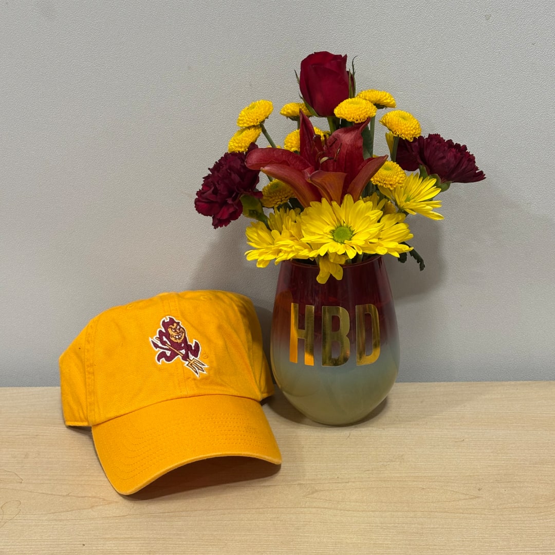 Mixed bouquet in a red vase beside a yellow baseball cap