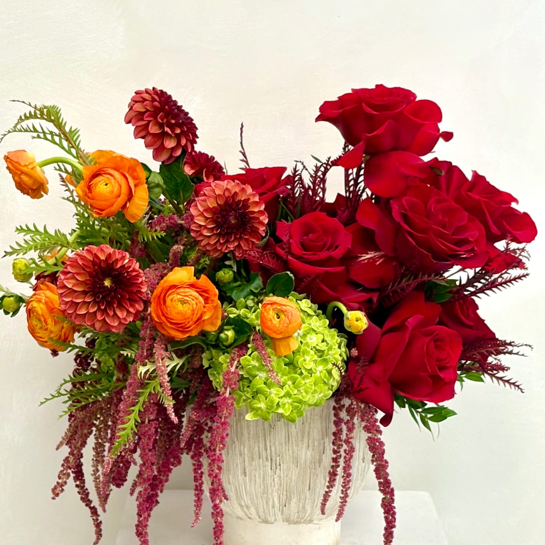 Red roses and orange ranunculus in a textured vase