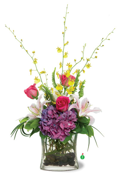 Pink roses and lilies in a glass vase with purple hydrangea and yellow sprays