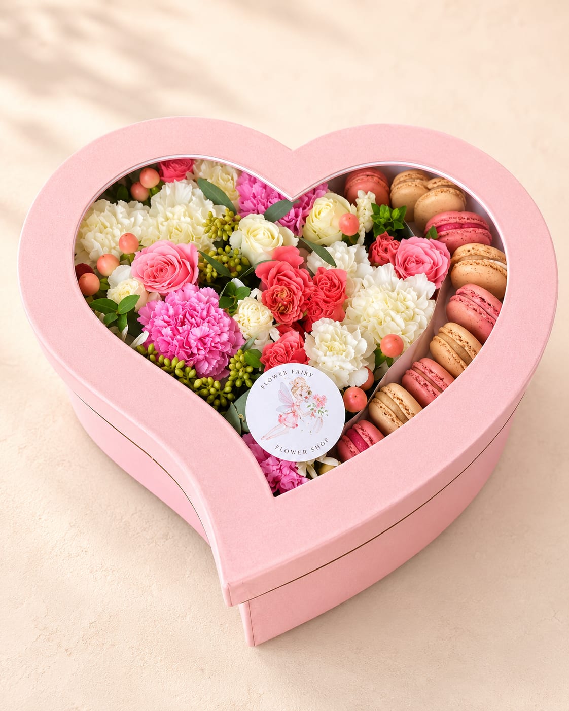 Charis' Sweet Surprise – Heart Flower Box with Macarons - Inspired by Charis, one of the Greek Three Graces and a symbol of beauty, charm, and generosity, Charis' Sweet Surprise is a luxurious heart-shaped flower box designed to create unforgettable moments.  This elegant gift pairs premium seasonal flowers with delicious gourmet macarons, bringing together timeless floral beauty and a delightful sweet treat. Arranged in a keepsake heart-shaped box, it offers a thoughtful way to celebrate birthdays, anniversaries, Valentine's Day, proposals, hotel welcome surprises, congratulations, or simply let someone know they're loved.  Every arrangement is handcrafted by Flower Fairy using the freshest flowers available. While flower varieties, colors, or macaron flavors may occasionally vary due to seasonal availability, we always preserve the overall style, presentation, and premium quality of every design.  Features: * Premium seasonal flowers * Gourmet assorted macarons * Elegant heart-shaped keepsake box * Handcrafted by Flower Fairy * Perfect for birthdays, anniversaries, Valentine's Day, hotel welcome gifts, proposals, and romantic surprises * Same-day flower delivery available throughout Phoenix, Scottsdale, Paradise Valley, Tempe, Chandler, Mesa, Glendale, Peoria, and the surrounding Phoenix Metro Area.