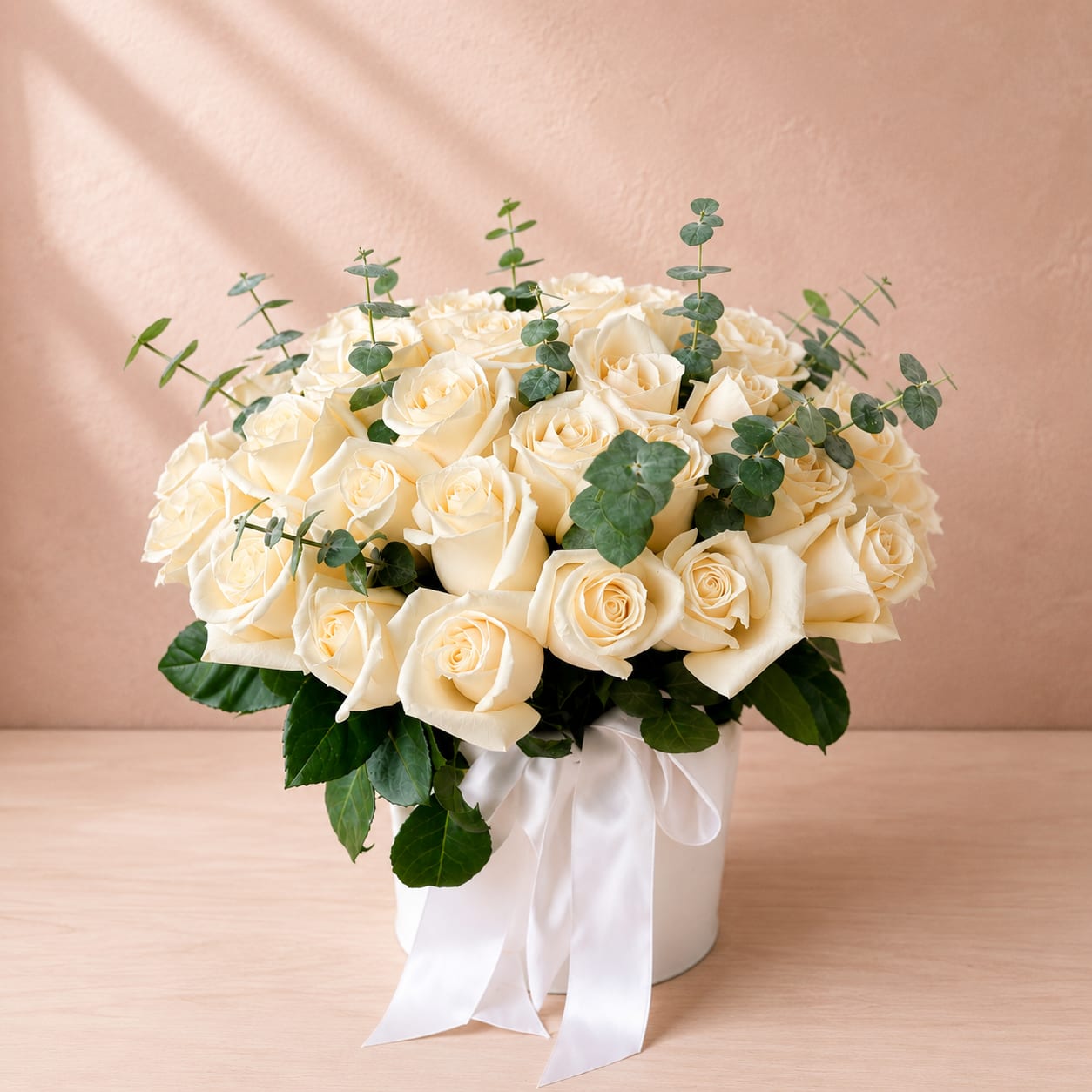 Pax's Ivory Remembrance Hat Box - Pax's Ivory Remembrance Hat Box is a timeless tribute that offers comfort, love, and heartfelt remembrance. Featuring lush premium ivory roses arranged in Flower Fairy's signature white hat box and accented with fresh eucalyptus, this sophisticated design creates a graceful expression of compassion during life's most difficult moments.  The soft ivory roses symbolize purity, honor, and eternal love, making this arrangement a beautiful choice for funeral services, memorials, celebrations of life, or sending condolences to family and friends. The luxurious hat box presentation offers a contemporary alternative to a traditional vase while creating an elegant keepsake long after the flowers have been enjoyed.  Each arrangement is handcrafted using the freshest premium blooms, ensuring a unique design that reflects both beauty and heartfelt sentiment.  Perfect For: Funeral Services Memorial Services Celebration of Life Sympathy &amp; Condolences Sending Comfort Thinking of You White-Themed Memorial Tributes  Features: Premium ivory roses Fresh eucalyptus accents Elegant white luxury hat box Handcrafted by Flower Fairy designers Modern, all-around presentation Keepsake hat box container Same-day local delivery throughout the Phoenix metro area