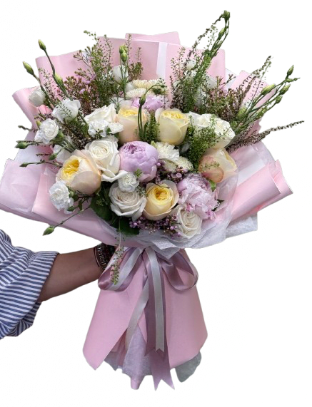 Pastel Serenade Bouquet by The Flower Spot - Pale cream and white roses mingle with peonies, soft pink carnations and white lisianthus in a rounded, hand-tied flower arrangement that reads like a gentle springtime embrace - a perfect birthday bouquet, anniversary flowers, or everyday gift to show someone you're thinking of them. The pastel color story of pink, white, purple, and touches of yellow creates a calm, celebratory mood that will make the recipient feel seen and cherished.  Each bloom is curated and arranged with a loose, garden-style texture: tall airy stems and fine filler add movement and a delicate, textural contrast to the fuller roses and carnations. The bouquet is finished in pink wrapping paper with white tissue and tied with a satin ribbon for a soft, romantic presentation that arrives ready to display.  Ideal for celebrating milestones or brightening an ordinary day, this bouquet suits mothers, partners, friends, or anyone who appreciates a refined, feminine palette. For best enjoyment, trim stems and change the water every two days; if ordering for a specific date, please select delivery on the day you want the bouquet to arrive