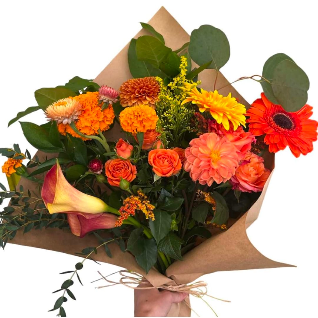 Bouquet of orange and yellow flowers with calla lilies and roses in brown paper