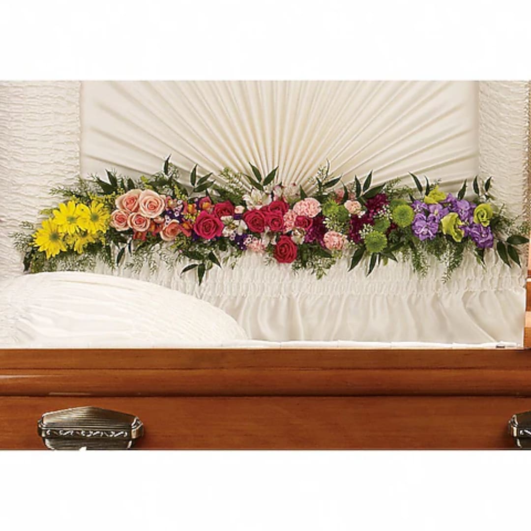 Colorful floral spray arranged across a white casket