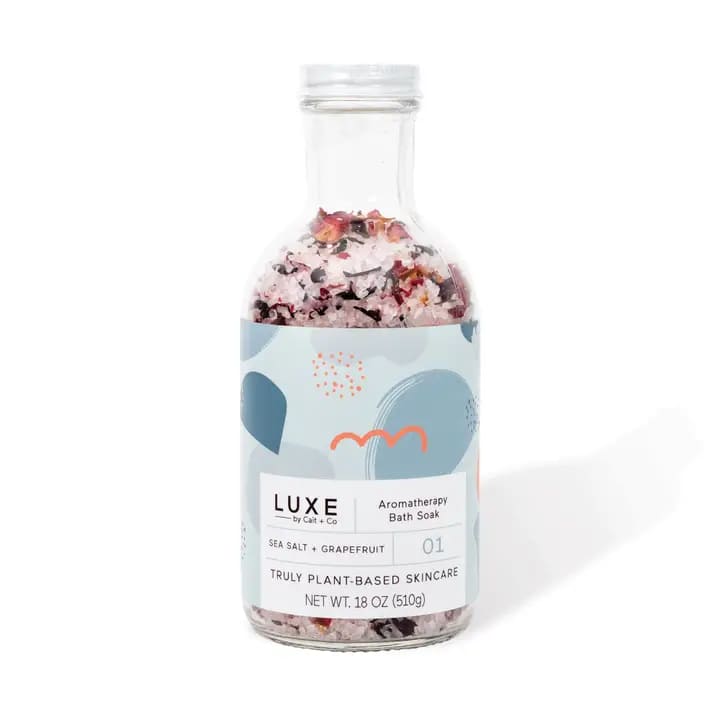 Bottle of aromatherapy bath soak with pink salt and dried petals