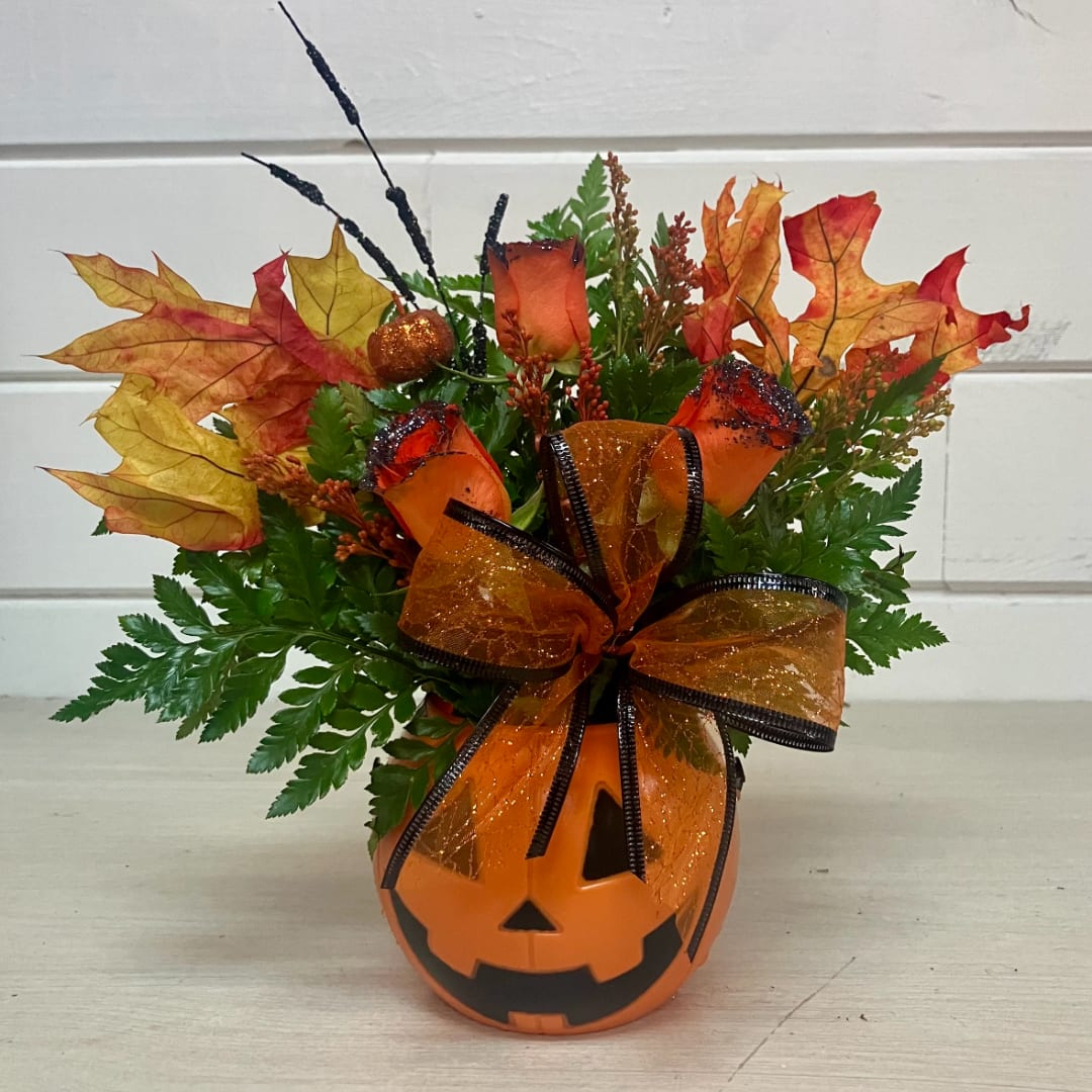 Halloween pumpkin container with orange flowers and autumn leaves