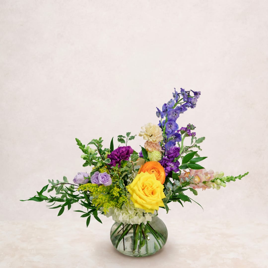 Colorful mixed bouquet in a round glass vase