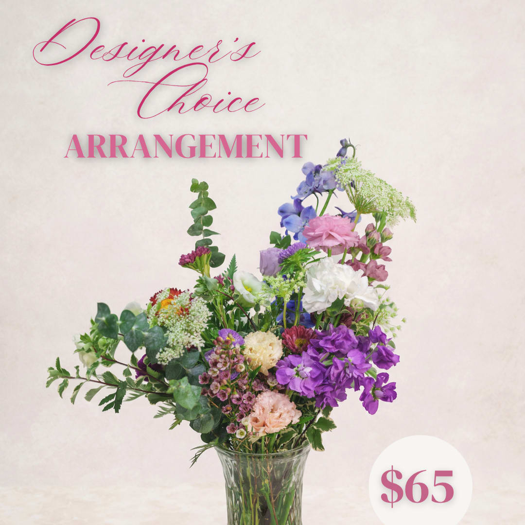 Mixed bouquet of purple, pink, and white flowers in a clear glass vase