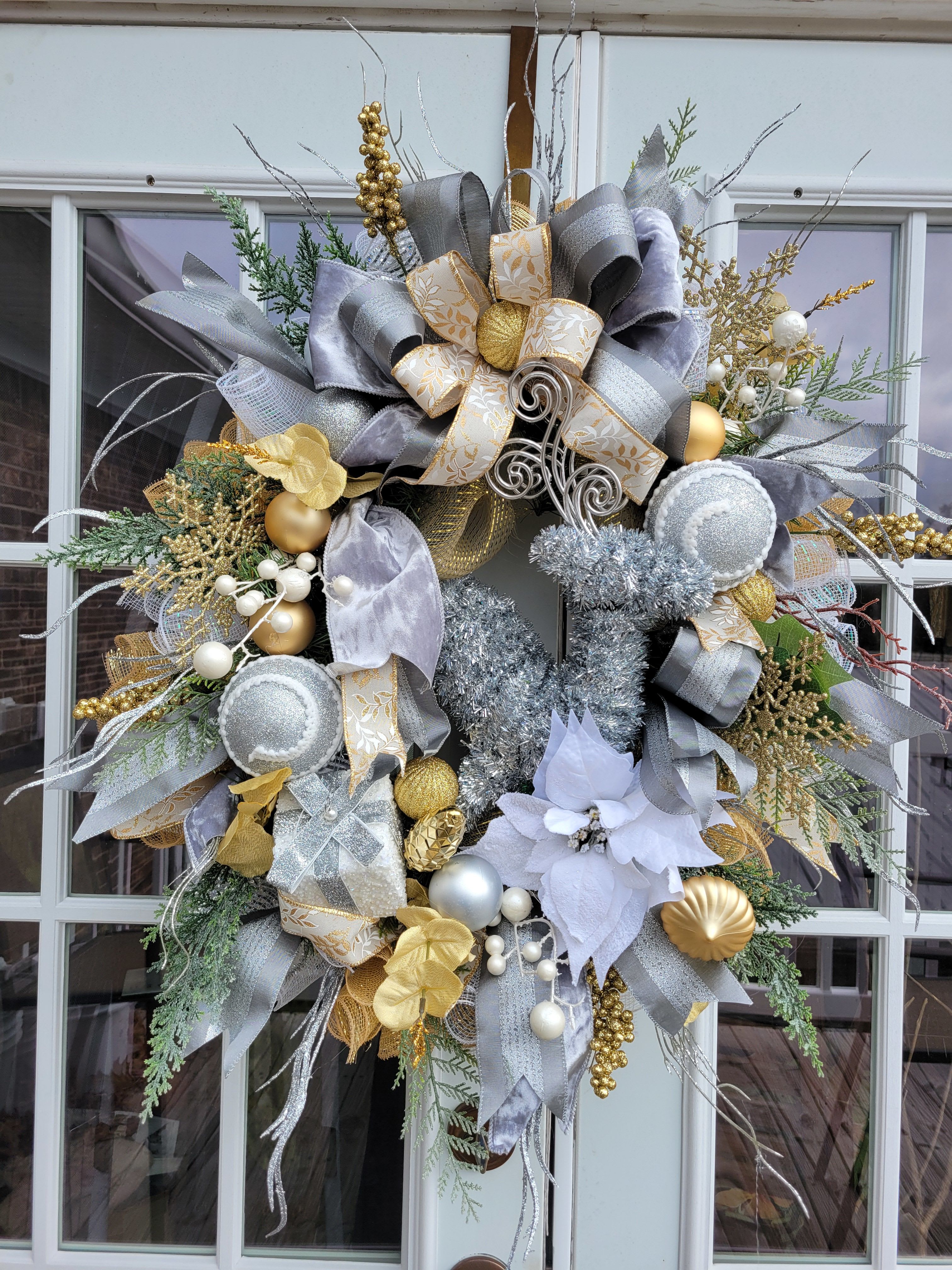 Decorative holiday wreath with silver, gold, and white ribbons and ornaments