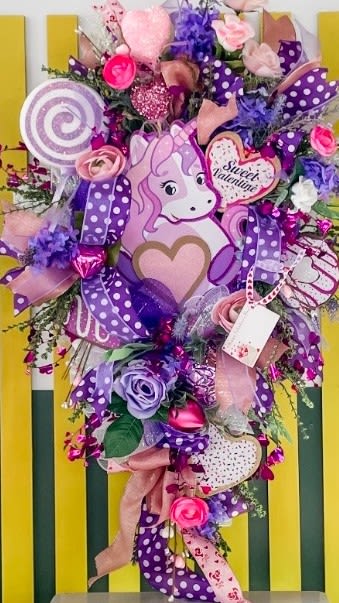 Unicorn-themed bouquet with pink and purple flowers, ribbons, and candy decorations