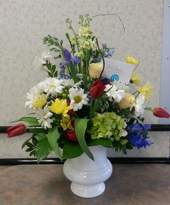 Mixed bouquet of daisies, tulips, and roses in a white vase