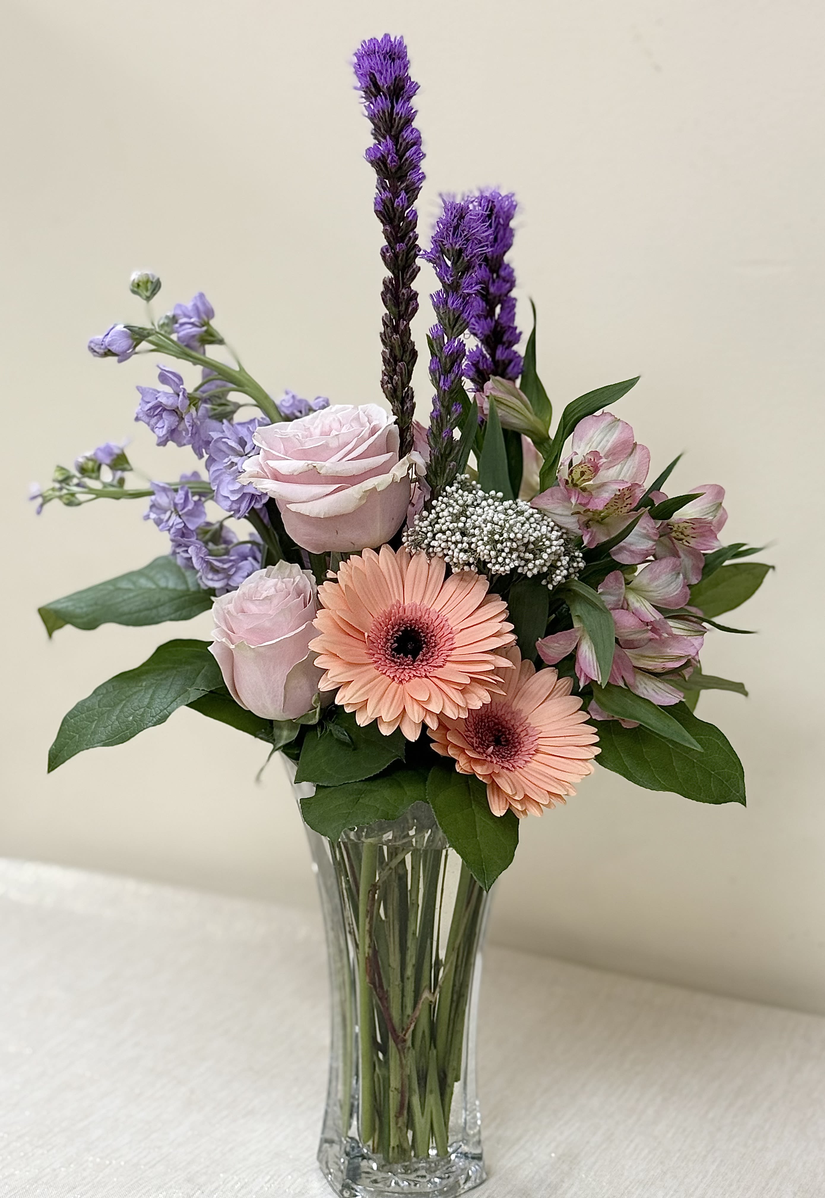 Mixed bouquet of pink and purple flowers in a clear glass vase