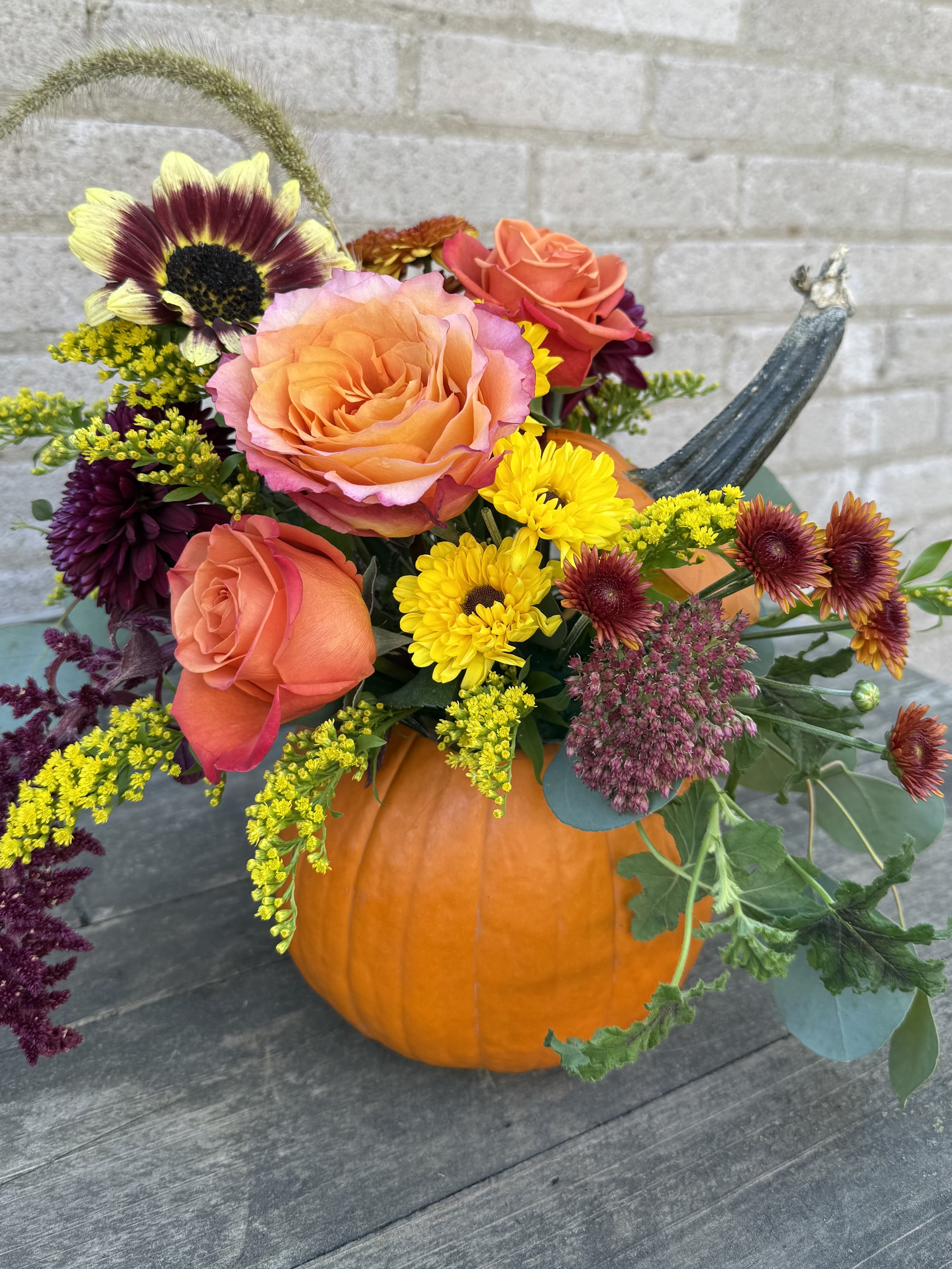 Fall bouquet in a pumpkin with roses and chrysanthemums