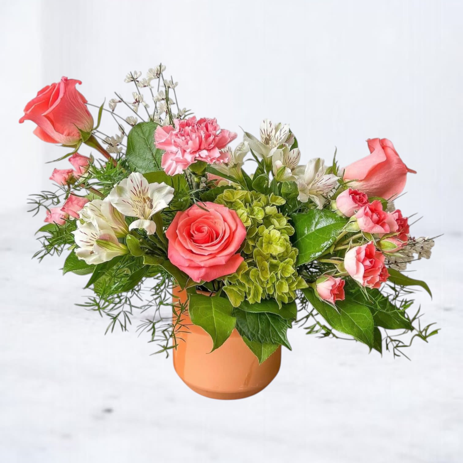 Blush Charm - Blush Charm is a sweet and vibrant arrangement featuring cheerful coral roses, bright green hydrangea, soft white alstroemeria, and playful pink carnations. Accented with fresh greenery and arranged in a sleek peach ceramic vase, this design radiates joy and warmth. Perfect for birthdays, anniversaries, get well wishes, or simply to brighten someone’s day. Handcrafted by Twigs and Blooms and available for same-day delivery in Friendswood, League City, Galveston, Alvin, Dickinson, and surrounding areas.  Substitution Policy: At Twigs and Blooms, we use only the freshest seasonal blooms. In rare instances, substitutions may be necessary to ensure your arrangement arrives at peak freshness while maintaining the original design style, color harmony, and full value.
