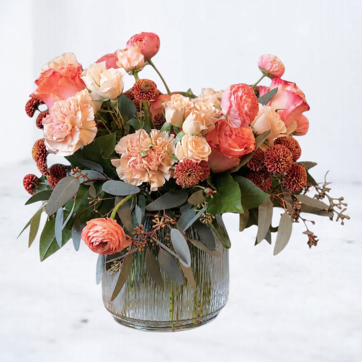 Peach and coral flower arrangement in a clear glass vase