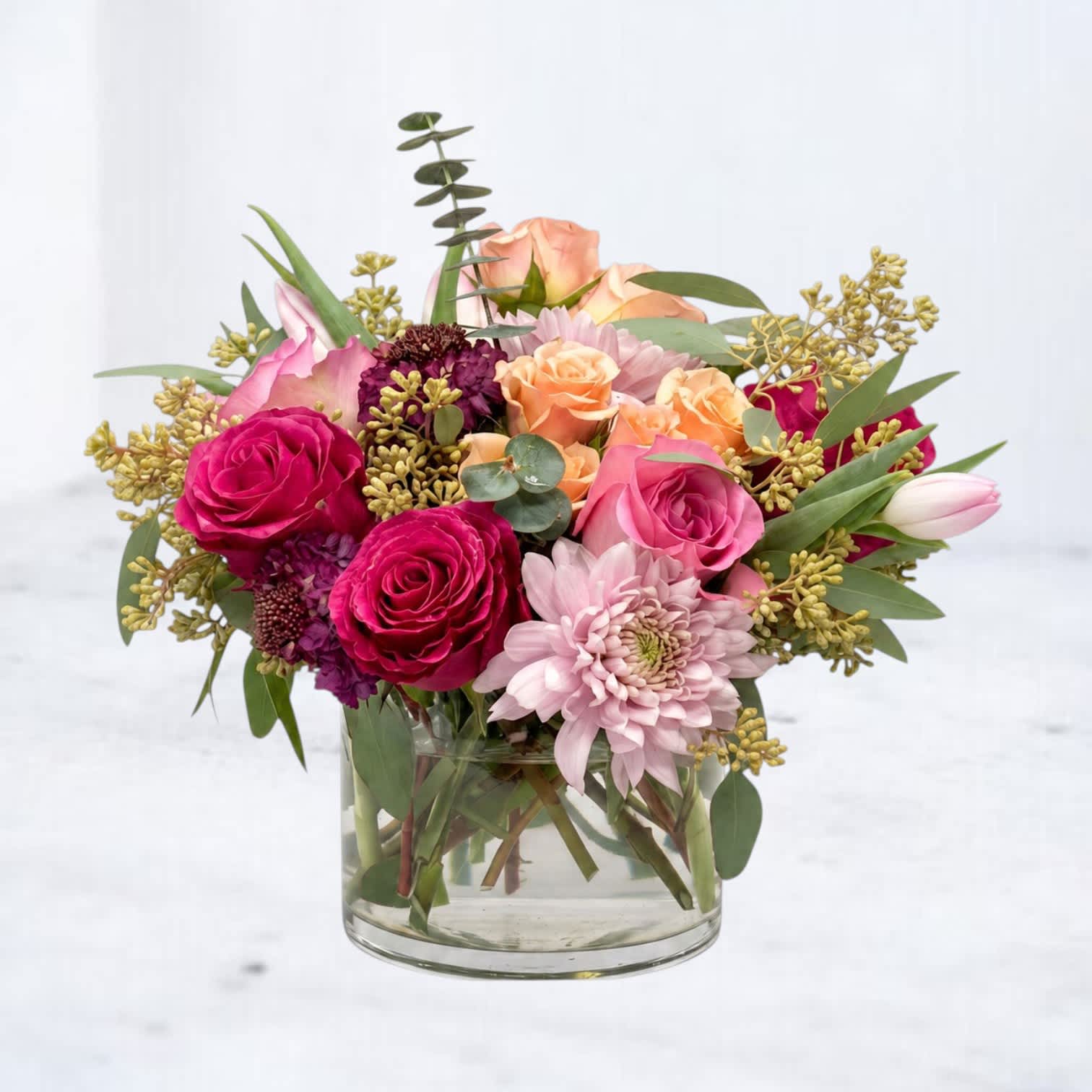 Mixed pink and peach flowers arranged in a clear glass vase