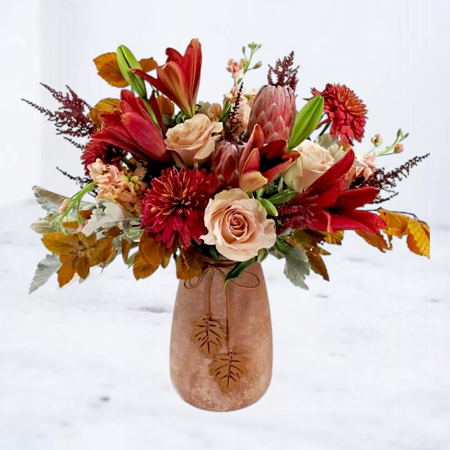 Autumn bouquet of red lilies and pale roses in a blush vase