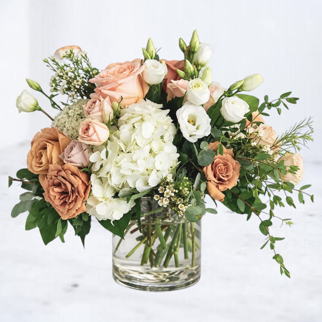 Peach and white roses with hydrangea in a glass vase