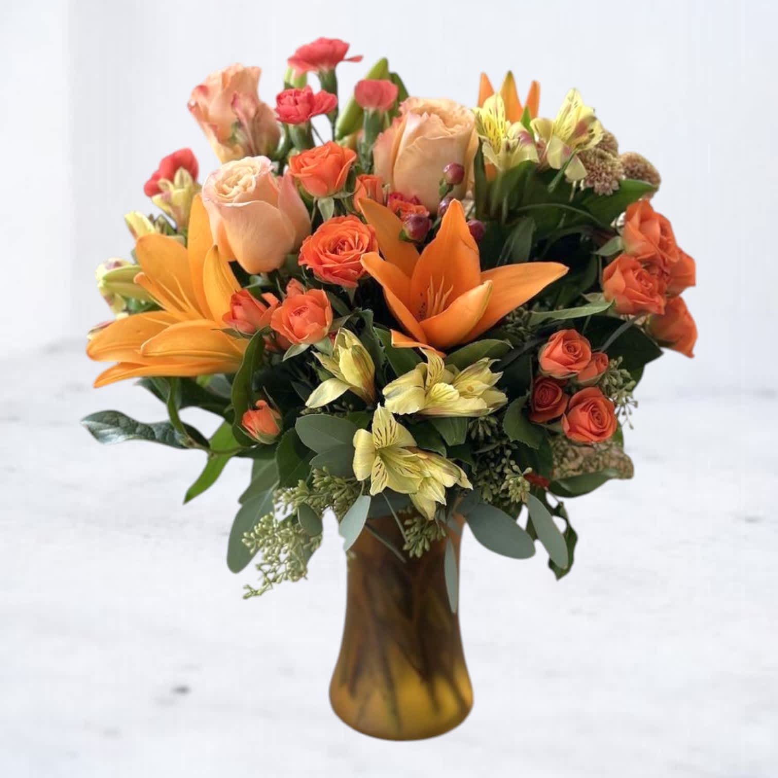 Bouquet of orange and peach flowers in a brown glass vase