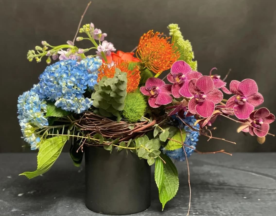 Japanese Garden - A serene and elegant design inspired by traditional Japanese gardens. This arrangement features Blue Hydrangeas, Pincushions, Stock, Roses, and graceful Phalaenopsis Orchids.  Please note: Orchid color may vary based on availability.