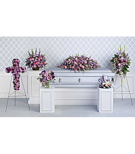 Funeral casket surrounded by pink and purple floral sprays