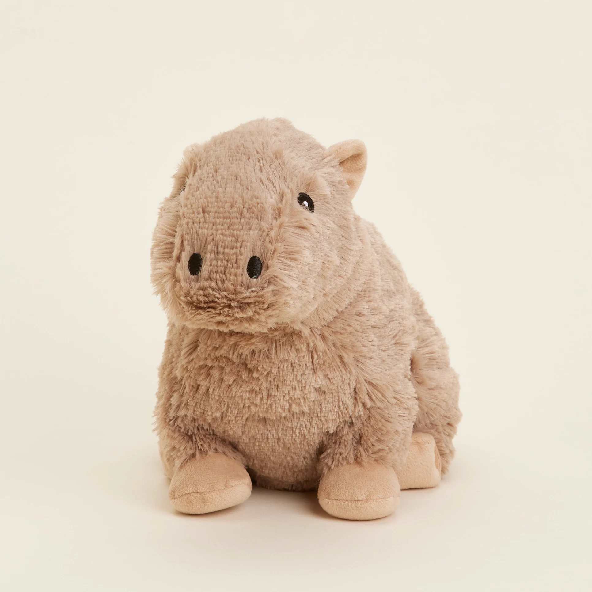Small tan plush animal toy sitting upright on a light background