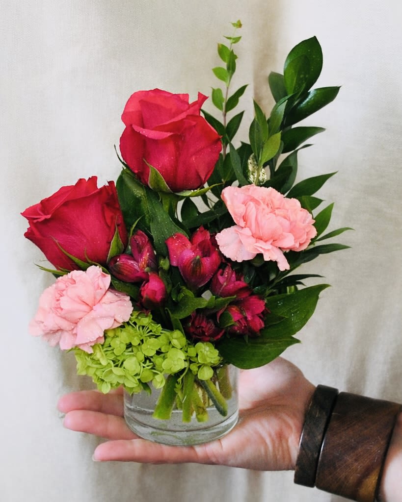 Mini Watermelon  - A bright, cheerful hand-held arrangement with hot pink roses, soft pink carnations, magenta alstroemeria, and fresh green hydrangea. Styled in a small glass vase with clean greenery for a fresh, modern look.