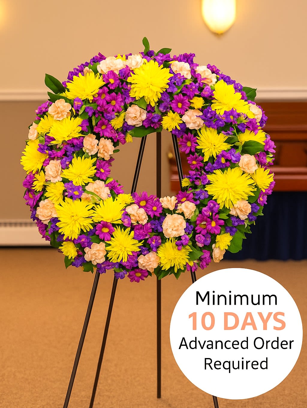 Standing wreath of yellow, purple, and peach flowers on a metal easel